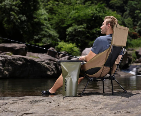 Man sitting on Lightweight Folding High Back Camping Chair With Head Support For Outdoor Adventures by a river
