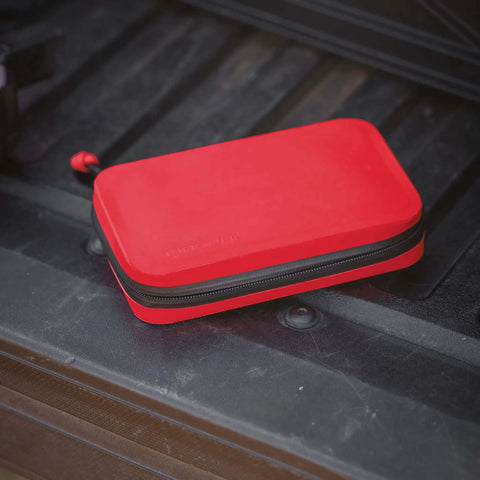 Ultra Slick Compact Semi Rigid Utility Organizer Case Built Tough With Weather Resistant Shell For Quick Tool Kit First Aid Electronics And Sweet Travel Gear Stash In Bold Red lying on a truck bed.