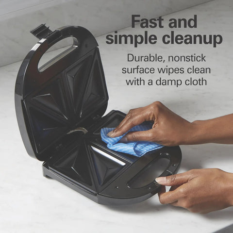 Hamilton Beach Electric Sealed Sandwich Maker Grill For Hot Pockets And Grilled Cheese, nonstick surface being wiped clean.