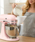 Person using Mess-Free Flour Funnel Attachment for Stand Mixers with Extended Splash Guard while adding flour to tilt-head bowl.