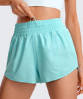 Close-up of turquoise high-rise running shorts with 2.5 inch inseam, elastic waistband, inner drawstring detail visible.