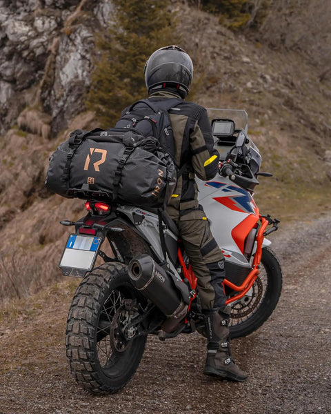 Rider on motorcycle with Waterproof Motorcycle Dry Bag 30L Duffle Tail Bag N Saddle Bags With Roll Top Closure in rugged terrain