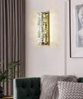 Lit Crystal Glass Wall Sconce In Gold Finish, Mid Century Modern Lighting on a living room wall, emitting soft light