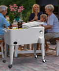 80 Quart Rolling Cooler Cart With Bottle Opener And Drainage On Wheels Portable Patio Beverage Cart For Pool Deck Outdoor Parties And Cookouts White Great For Summer with drinks on a patio.