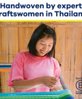 Woman weaving with colorful threads, wearing pink shirt, showcasing handwoven craftsmanship in Thailand.