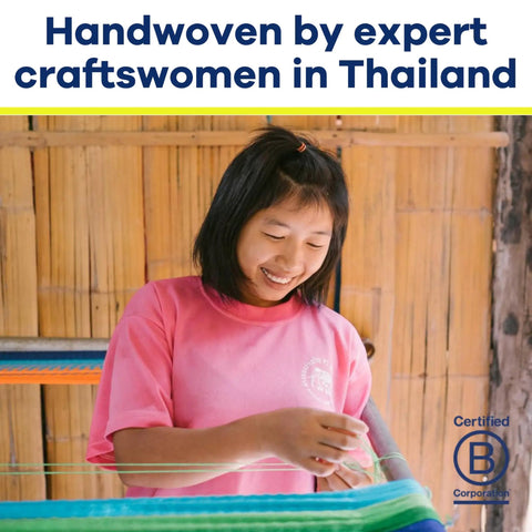 Woman weaving with colorful threads, wearing pink shirt, showcasing handwoven craftsmanship in Thailand.