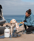 Woman washing dog with High Pressure 5L Portable Shower Kit Hand Pump 45 PSI No Power Needed for Camping Outdoor Rinse Beach Dog Wash