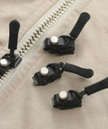Zipper Repair Kit Puller Replacement Tool Three Piece Set With Easy Grip Design on a beige fabric with black pullers