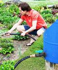 Man using Rain Barrel Spigot Kit With Hole Saw, PVC Bulkhead Fitting, Ball Valve, Thread Seal Tape, And Garden Hose in garden