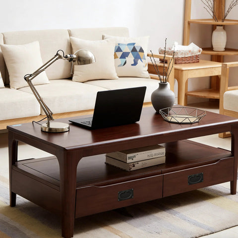 Modern living room with wooden coffee table, laptop, and decorative items; sofa and shelf in background.