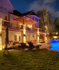 12 Inch LED Up Down Cylinder Outdoor Wall Light 3000K Warm White 120-277V Dimmable Aluminum Waterproof Exterior Porch Sconce ETL Listed Front Door Lighting Pack Of 2 illuminating a modern house exterior by poolside at night.