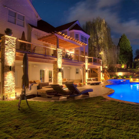 12 Inch LED Up Down Cylinder Outdoor Wall Light 3000K Warm White 120-277V Dimmable Aluminum Waterproof Exterior Porch Sconce ETL Listed Front Door Lighting Pack Of 2 illuminating a modern house exterior by poolside at night.