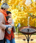 Family with children near a vintage outdoor metal bird bath with free standing stake and detachable feeder bowl in antique bronze finish.