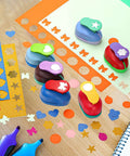 Six Shape Hole Punch Set For Kids 1 Inch Shape Punches on table with cardstock sheets for scrapbooking and DIY crafts
