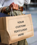 Person holding Logo Ready Printed Kraft Paper Bags 100 Pack With Handles 12.6 X 4.3 X 9.8 Inches Brown Gift Bags For Branding