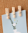 100 Piece Natural Wood Push Pin Clip Set Includes Clear Tube To Tidy Up Papers And Memos No Fuss Thumb Tacks For Clean Desk Setup Goals, holding a note.