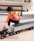 Child playing with Peterbilt Model 367 Semi Truck Toy With Grain Trailer One Sixteen Scale Die Cast And Plastic Durable Construction Vehicle