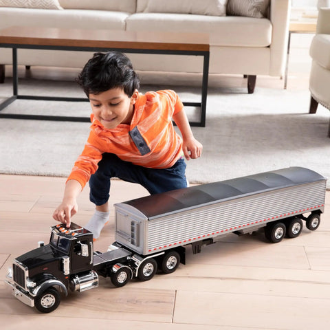 Child playing with Peterbilt Model 367 Semi Truck Toy With Grain Trailer One Sixteen Scale Die Cast And Plastic Durable Construction Vehicle