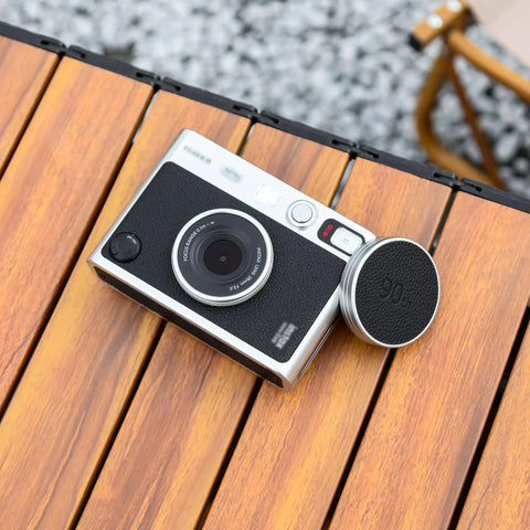 Leather Lens Cap For Insta Mini Evo Camera, Aluminum Anti Dust Anti Scratches Lightweight Lens Cover With Soft EVA Interior on table.