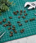 Rock Solid 30 Piece Full Replacement Ceiling Fan Blade Screws With 1/4-20 Threading And Premium Bronze Pan Heads on green grid surface.