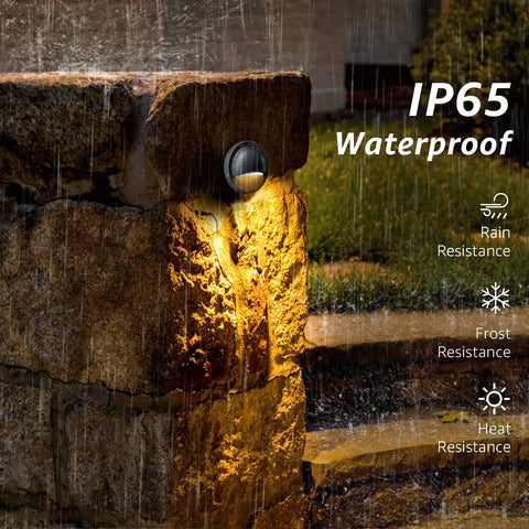 Low Voltage LED Deck Lights 12-24V 6 Pack illuminating a stone pillar in rain, showcasing IP65 waterproof and warm 3000K glow