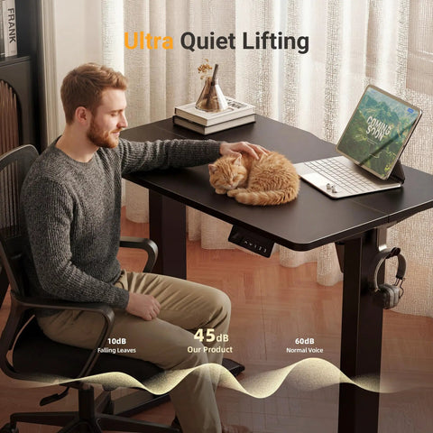 Man sitting at 32 Inch Electric Standing Desk For Small Spaces With Adjustable Height Sit Stand Memory Presets And Cable Management, black frame, black top