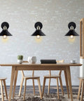 Dope Industrial Vintage Black Wall Sconces Set Of 3 Hardwired With Adjustable Heads mounted on a white brick wall above a table.