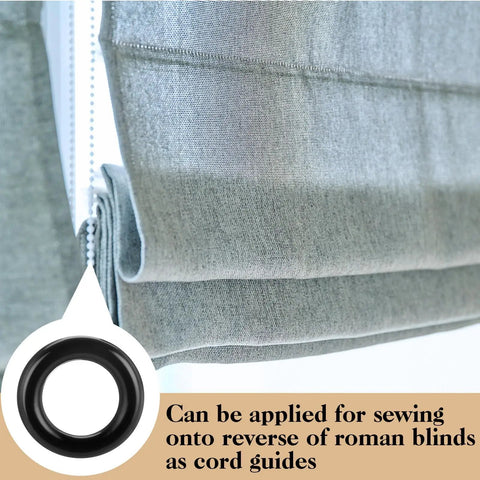 Black plastic Roman blind curtain ring O ring attached to a gray fabric blind, used as a cord guide for window treatments.