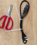 1000 Count 4 Inch Heavy Duty Cable Zip Ties securing black power cable, with red scissors on wooden surface.