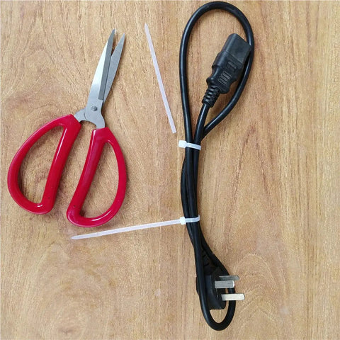1000 Count 4 Inch Heavy Duty Cable Zip Ties securing black power cable, with red scissors on wooden surface.