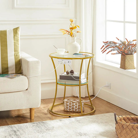 Round End Table With Charging Station And Glass Top beside sofa, featuring 2-tier gold accents and integrated power outlets.