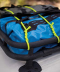 Gear Tie Mega Rubber Twist Tie 32 Inch Bright Orange secures blue tarp on roof rack, strong bendable wire core visible.