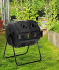 43 Gallon Outdoor Tumbling Compost Bin With Dual Chamber Sliding Doors for Garden and Patio on grass near garden beds.