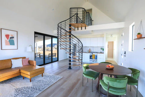 Modern living room with spiral staircase, green chairs, and wooden dining table