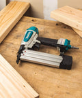 Renewed 18 Gauge Pneumatic Brad Nailer For DIY Pros with aluminum body on a woodworking bench, surrounded by wooden planks.