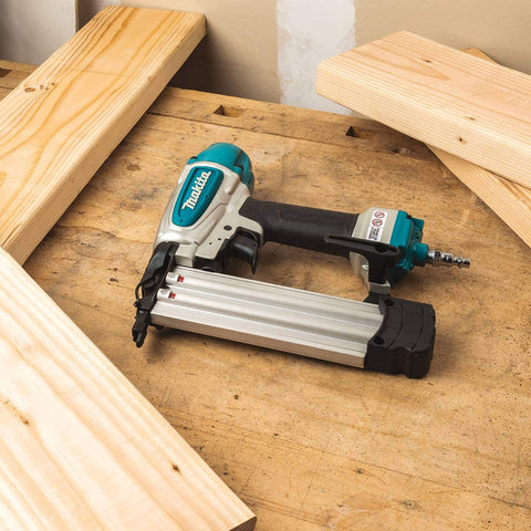 Renewed 18 Gauge Pneumatic Brad Nailer For DIY Pros with aluminum body on a woodworking bench, surrounded by wooden planks.