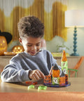Child assembling a mini haunted house with 24 Piece Halloween Magnetic Building Tiles For Kids To Build A Mini Haunted House Featuring Spooky Neon Blocks Portable Travel Case And Next Level Sick Creativity Fun.