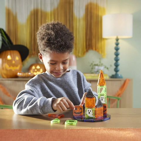 Child assembling a mini haunted house with 24 Piece Halloween Magnetic Building Tiles For Kids To Build A Mini Haunted House Featuring Spooky Neon Blocks Portable Travel Case And Next Level Sick Creativity Fun.