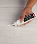 Applying Quick Fix Putty For Wood Laminate And Vinyl Floors Acrylic Based Gap Filler In White to floor surface.