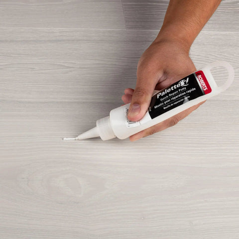 Applying Quick Fix Putty For Wood Laminate And Vinyl Floors Acrylic Based Gap Filler In White to floor surface.