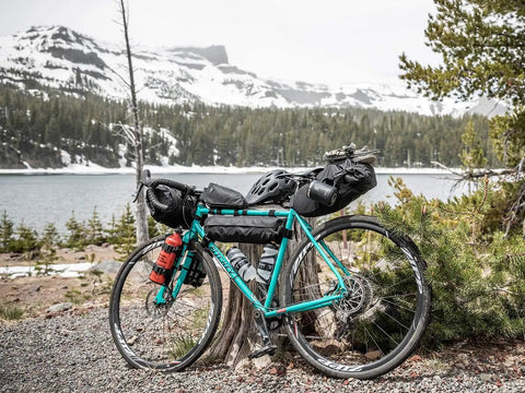 MidLoader Four Point Five Liter Bike Frame Bag For Bikepacking And Gravel Touring on turquoise bike by a mountain lake.