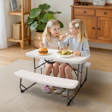 Girls seated at white picnic table with benches indoors, using Picnic Table With Benches Set For Outdoor And Indoor Use All Weather Steel Frame Stable And Easy To Clean Your Go To Portable Camp Table And Chairs Fold Flat Lightweight And Durable.