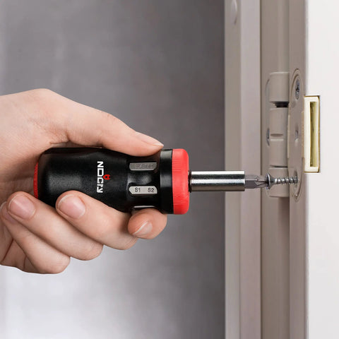 Person using Stubby Ratcheting Screwdriver Kit With 14-In-1 Mini Bit Set Including Flathead, Hex, Torx, Square, And Pozidriv Tips Compact Black And Red Dope Handy Tool For Quick Fixes And Electronics Projects on a door hinge