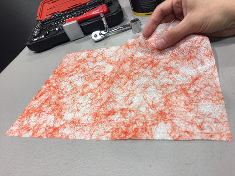 Person holding a Grease Busting Heavy Duty Hand And Tool Wipe for Degreasing Hands And Work Surfaces near tools