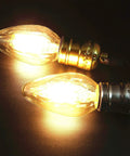 Close-up of 8W LED Porch Light Bulb Dimmable 2700K Warm White E26 Base Outdoor Post Light For Ceiling Fans And Lanterns Vintage Filament Wrinkle Glass 75W 80W Equivalent No Brainer 4 Pack in glowing operation showcasing wrinkle glass and filament design.