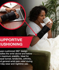 Image of a person wearing an Adjustable Night Wrist Brace For Sleep With Comfy Cushioned Support And 360 Degree Coverage Left Or Right Fit One Size Fits Most Black Gentle Arm Compression For Pain Relief And Comfort, sitting on a couch while drinking a beverage.