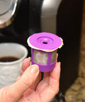 Straight Up Heavy Duty Unbleached Paper Filters With Lid For Reusable K Cups 700 Count Box in hand near coffee maker.