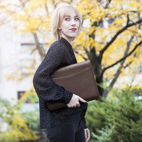 Woman holding the Career Game Changer Business Padfolio With Heavy Duty Zipper Closure Crafted From Smooth Pu Vegan Leather in rich brown.