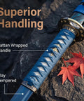 Beast Mode Spring Steel Katana Hand Forged Plum Blossom Samurai Sword with blue wrapped handle and blade detail on rocks.