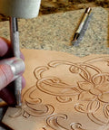 Level Up Your Leather Crafting Game With This Sweet Beginner Tooling Kit Featuring A Sharp Swivel Knife Six Essential Stamps Veg Tan Patterns And A Nifty Instructional Booklet For Dope Custom Designs, depicting a hand using a swivel knife on a leather piece.